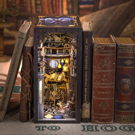 The Nebula Common Room Book Nook by Tonecheer is a beautifully crafted DIY kit that creates a miniature library scene. The intricate detailing features bookshelves filled with books, ornate decorations, and a cozy atmosphere, illuminated by a soft light. This decorative piece is designed to fit between standard books on a shelf, adding a whimsical touch to any space.