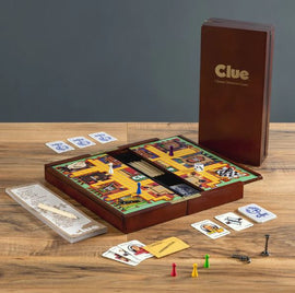 The Clue Deluxe Travel Edition game by Winning Solutions is displayed on a wooden surface. The game board is open, featuring a colorful layout with rooms, character pieces, dice, and cards neatly arranged. The elegant wooden box is partially visible, showcasing the brand name in gold. Accessories like the score sheet and detective notes accompany the game, highlighting its classic detective theme.