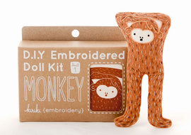 Monkey Doll Embroidery Kit by Kiriki Press featuring a cute, handcrafted monkey doll design. The kit comes in a level 1 difficulty, perfect for beginners who want to explore DIY embroidery. The packaging showcases the signature monkey illustration, and the doll is displayed in a lively orange color, ready to be stitched.