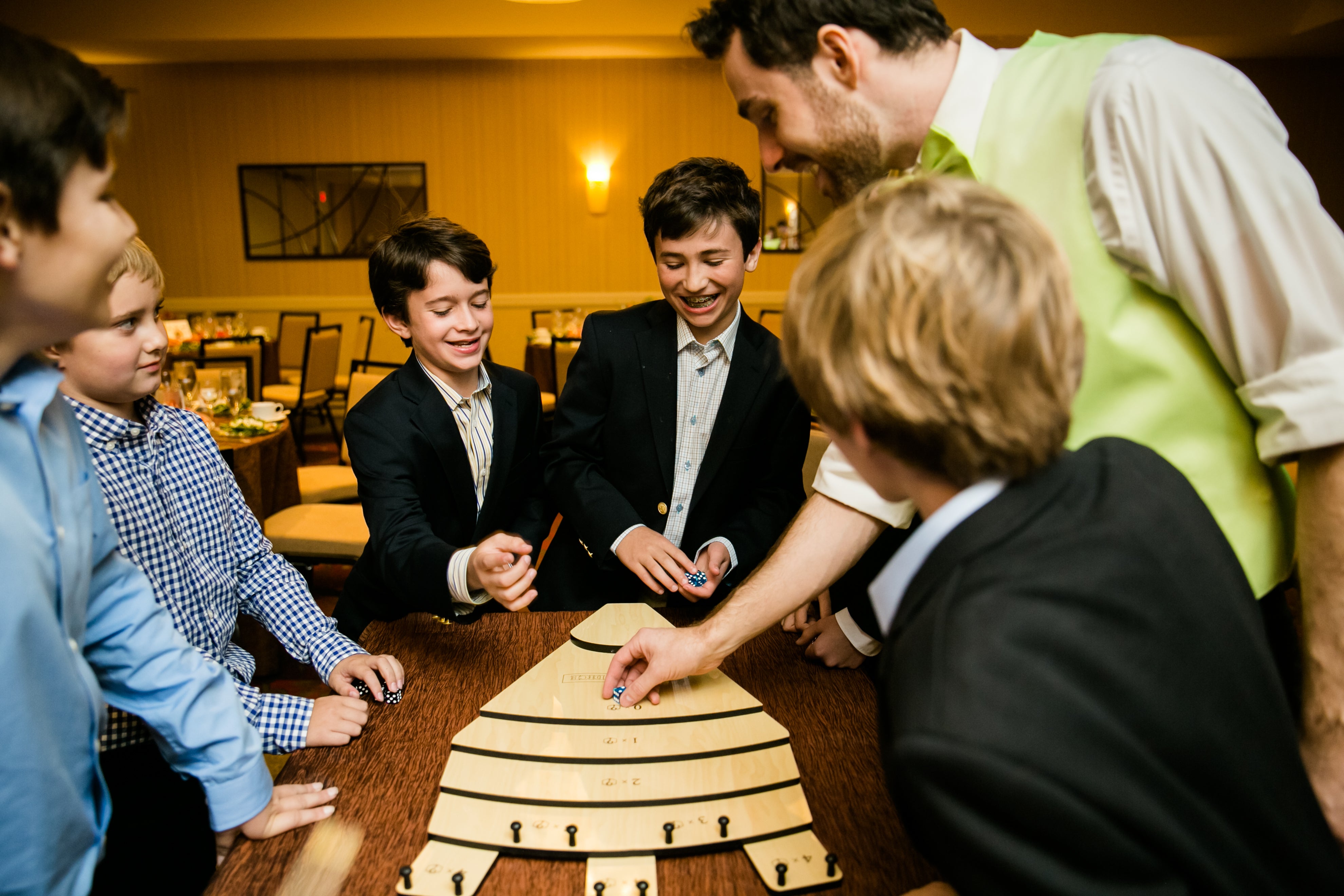 A group of pre-teen boys crowd around a game of Tumblin Dice. 