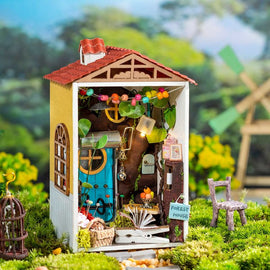 The Borrowed Garden Model Kit by Robotime is a charming DIY miniature house kit featuring a colorful exterior with a red roof and a vibrant blue door. Inside, it showcases intricate details like furniture, decorative lights, and greenery, crafting a delightful forest house scene. Perfect for creative individuals looking to build their own enchanting garden retreat.