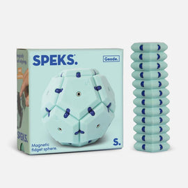 Speks Geode: Mile High is a magnetic fidget sphere featuring a unique hexagonal design in a soothing mint color with navy accents. The product packaging displays the name 'SPEKS' prominently, while a stack of geometric pieces stands beside the sphere, inviting exploration and interaction.