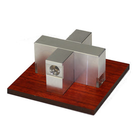 Aluminum Sweta Cross mechanical puzzle by W.G.H. Strijbos displayed on a wooden base. The puzzle features a unique cross-shaped design with polished aluminum blocks and small spheres, emphasizing both creativity and engineering.