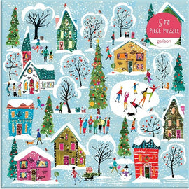 A colorful 500-piece jigsaw puzzle titled 'Twinkle Town' by Galison, depicting a festive winter scene with houses, trees, and people enjoying snow activities. The illustration features decorated homes, snowy landscapes, and joyful figures engaged in various winter festivities, including singing and playing, set against a light blue background.