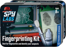 The Spy Labs Fingerprinting Kit by Thames & Kosmos features a colorful package showcasing a fingerprinting brush, a bottle for fingerprint powder, and prints displayed on paper. The background illustrates a scene with broken glass and a window, indicating a mystery to solve. Suitable for ages 8 and up, this kit encourages kids to explore forensic science through hands-on activities.