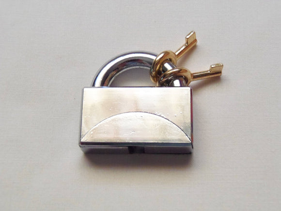 A vibrant Two Key Lock Puzzle by Bits and Pieces, featuring a shiny silver padlock design. The puzzle includes two gold keys, emphasizing its mechanical challenge for puzzle enthusiasts.