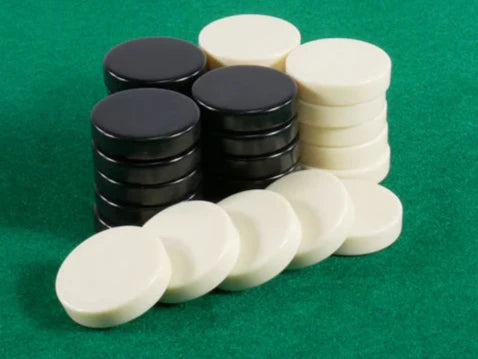 A collection of checkers game pieces featuring 1.25-inch black and ivory tokens stacked in alternating colors. The pieces are arranged neatly on a green felt surface, ideal for various board game setups.