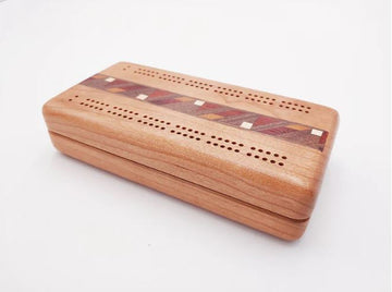 A beautifully crafted Cherry Cribbage board made from cherry wood with decorative inlays. The board features precision-drilled holes for scoring and a smooth finish, showcasing the fine craftsmanship by Heartwood Creations.