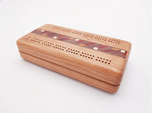 A beautifully crafted Cherry Cribbage board made from cherry wood with decorative inlays. The board features precision-drilled holes for scoring and a smooth finish, showcasing the fine craftsmanship by Heartwood Creations.
