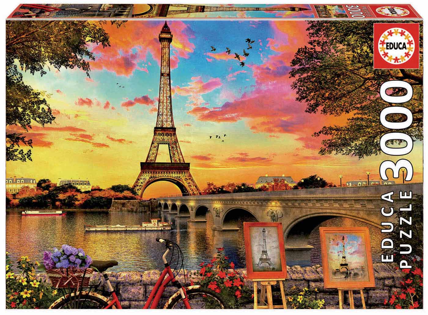 A vibrant jigsaw puzzle titled 'Sunset in Paris' by Educa, featuring a stunning sunset view of the Eiffel Tower over the Seine River, framed by trees and colorful flowers. The scene includes a charming bicycle with a basket of flowers and paintings of the Eiffel Tower displayed along the riverbank.