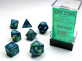 Chessex Festive green and silver polyhedral dice set displayed with a clear packaging. The set includes seven dice featuring various shapes: a D4, D6, D8, D10, D12, D20, and a D percentile, all showcasing vibrant green and silver colors with white numbering.