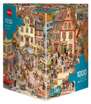 The 'Market Place' jigsaw puzzle by Göbel & Knorr, produced by Heye, features a vibrant scene of a bustling market with people, colorful stalls, and charming buildings. This 1000-piece puzzle includes detailed illustrations and comes with a poster.