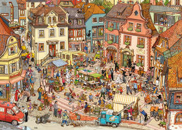 A vibrant jigsaw puzzle illustration titled 'Market Place' by Göbel & Knorr, featuring a bustling town square filled with people, market stalls, colorful buildings, and various activities such as dancing, shopping, and street performances. Lush greenery and detailed architectural elements enhance the lively atmosphere of the scene.
