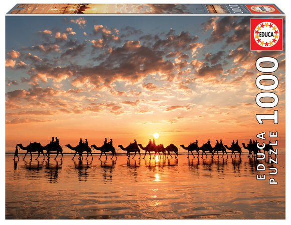 A beautifully illustrated jigsaw puzzle box featuring a stunning golden sunset over Cable Beach, Australia. The image depicts silhouetted camels and their riders walking along the beach, with vibrant orange and pink hues in the sky and tranquil reflections on the wet sand. The puzzle includes 1000 pieces, making it a perfect challenge for puzzle enthusiasts.