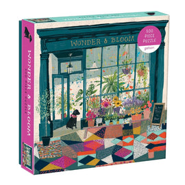 Wonder and Bloom jigsaw puzzle by Galison features a charming illustration of a flower shop with colorful floral displays and a welcoming atmosphere. The 500-piece puzzle emphasizes vibrant colors and intricate details.