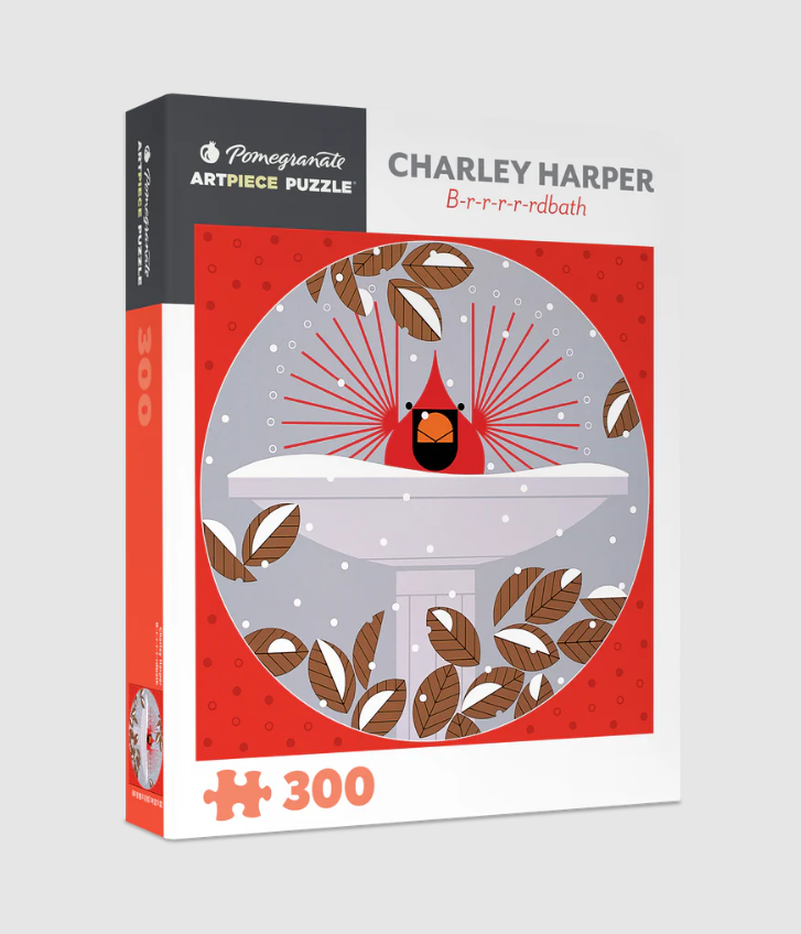 Charley Harper B-r-r-r-rdbath jigsaw puzzle by Pomegranate, featuring a vibrant illustration of a cardinal in a birdbath surrounded by snow and leaves. The puzzle contains 300 colorful pieces and is housed in a stylish box with artistic design elements.