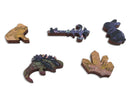 Five unique jigsaw puzzle pieces from the Mosslands collection by Artifact Wooden Puzzles. Each piece features intricate designs with earthy tones and vibrant patterns inspired by nature, showcasing a variety of shapes including animals and natural elements.