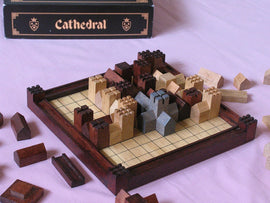 Cathedral board game by Family Games Inc. features a wooden playing board with various colored wooden building pieces arranged strategically. Some pieces are stacked to resemble towers, while others are placed around the grid. The game is designed for strategic thinking and tactical planning, suitable for family game nights or gatherings.