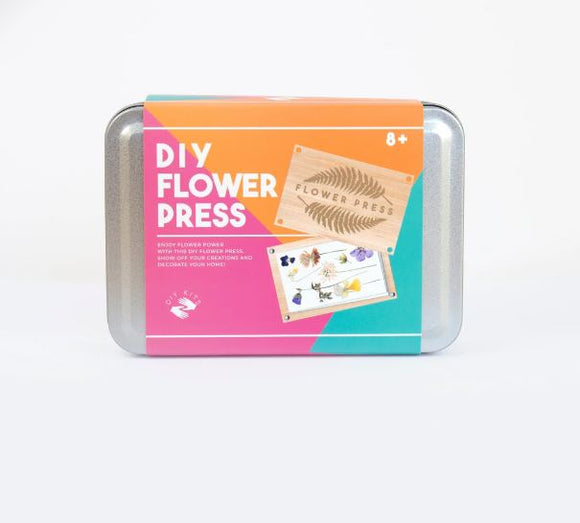 A DIY Flower Press kit packaged in a colorful tin box. The front features the words 'DIY Flower Press' in bold white letters against an orange background, with images of pressed flowers and a wooden board labeled 'Flower Press'. Suitable for ages 8 and up, this kit allows users to create beautiful pressed flower designs for decoration.