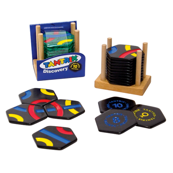 Tantrix Discovery mechanical puzzle set featuring colorful hexagonal tiles in blue, yellow, red, and black. The tiles are stacked on a wooden holder next to a blue box labeled 'Tantrix Discovery'. Each tile displays different numbers and patterns, inviting players to explore intricate designs and challenges.