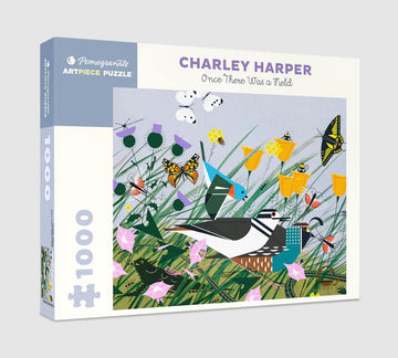 Once There Was a Field jigsaw puzzle by Pomegranate, featuring a vibrant illustration by Charley Harper. The image showcases colorful butterflies, birds, and flowers amidst lush green grass, designed with an artistic and playful style. This 1000-piece puzzle is perfect for wildlife enthusiasts and puzzle lovers alike, providing both a challenge and a delightful image to display once completed.