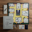 Clue Vintage Bookshelf Edition game setup showing the game board with rooms, pieces, dice, and clue cards. The box is designed to resemble a vintage book, adding a classic aesthetic.