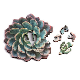 A beautifully crafted jigsaw puzzle featuring a mini succulent design. The puzzle is made of interlocking pieces showcasing shades of green and pink. Several pieces are displayed next to the assembled puzzle, illustrating the intricate details and unique shapes of the puzzle pieces.