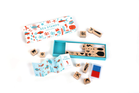 The Sea Stamps set features 25 wooden stamps with aquatic designs, including various sea creatures and plants, along with two ink pads. The colorful packaging showcases an underwater theme with illustrations of coral and fish, perfect for crafting and DIY projects.