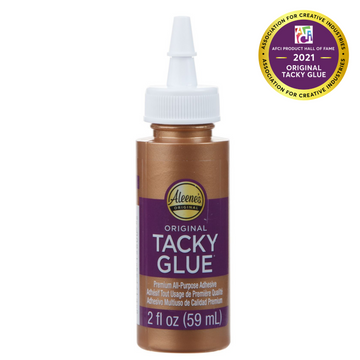 Aleene's Original Tacky Glue 2oz bottle in a shiny gold finish with a white nozzle cap. The label features a purple band with the product name and details about its all-purpose adhesive qualities.