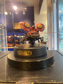 A detailed view of the Scout Beetle Mechanical Model by Robotime, showcasing its intricate design. The model resembles a futuristic robotic beetle with large red wings and mechanical details, mounted on a black circular base. It features gears and visual embellishments that highlight its craftsmanship, perfect for DIY enthusiasts and collectors.