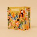 Monikers: Serious Nonsense is a colorful party game box featuring various illustrated characters engaged in fun activities. The design includes energetic people and whimsical elements, making it appear vibrant and inviting. The packaging is bright yellow, adorned with playful illustrations that suggest a lighthearted and entertaining gameplay experience.