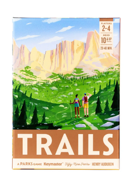 The box of 'Trails: A Parks Game' by Keymaster Games features a vibrant illustration of two hikers on a lush green trail surrounded by mountains. The adventurous scene invites players aged 10 and up to explore nature through gameplay, designed for 2 to 4 players with a playtime of 21-40 minutes.