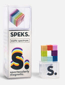 A colorful assortment of magnetic balls in a clear box labeled 'SPEKS: Matte Spectrum'. The product features vibrant matte colors arranged in a cube formation, showcasing the creativity and fun of building magnetic structures. The packaging is designed with a playful logo and warning information, emphasizing the toy's engaging nature.