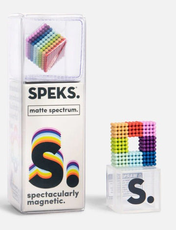 A colorful assortment of magnetic balls in a clear box labeled 'SPEKS: Matte Spectrum'. The product features vibrant matte colors arranged in a cube formation, showcasing the creativity and fun of building magnetic structures. The packaging is designed with a playful logo and warning information, emphasizing the toy's engaging nature.