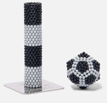 The Speks Elements: Lunar set features a tall cylindrical shape and a compact spherical design made from interlocking magnetic balls in black and white. The cylindrical piece showcases alternating black and white stripes, while the spherical piece resembles a soccer ball pattern. These pieces can be arranged in various shapes, promoting creativity and stress relief.