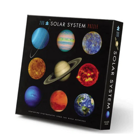 Crocodile Creek Solar System Jigsaw Puzzle featuring vivid images of the planets, including Earth, Saturn, and Mars. The puzzle box displays a colorful collage of celestial bodies, perfect for educational fun. Great for kids and space enthusiasts to engage in learning about the solar system through play.
