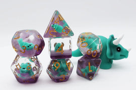 A vibrant Green Triceratops RPG Dice Set by Foam Brain. The set includes various polyhedral dice featuring cute, teal Triceratops figures encased in translucent purple material with golden numbers, showcasing a playful design perfect for tabletop gaming enthusiasts.