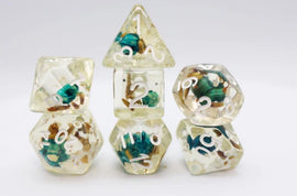 A set of five RPG dice known as the Morning Glory Seed RPG Dice Set, made by Foam Brain. The dice feature a transparent design filled with colorful flower petals and leaves, with white numerals clearly visible on each die. There are different shapes including a tetrahedron, cube, and dodecahedron, perfect for tabletop gaming enthusiasts.