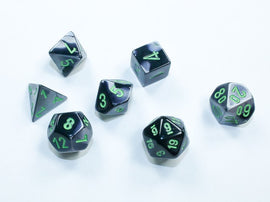 A set of Mini Gemini RPG dice in black and grey with bright green numbers. The set includes seven polyhedral dice, each displaying different shapes and numbers, ideal for tabletop gaming enthusiasts.