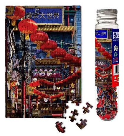 Micro Puzzle featuring a vibrant image of Chinese lanterns hanging in a bustling street market. The puzzle includes several interlocking pieces beside a clear storage tube, showcasing colorful pieces and a detailed visual of the scene.