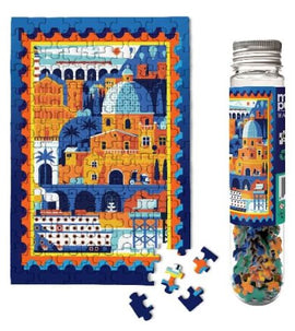Micro Puzzle Mediterranean Vacation jigsaw puzzle. The image shows a vibrant scene with colorful buildings, domes, and palm trees, completed puzzle alongside puzzle pieces in a bottle.