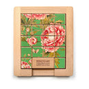A wood sliding puzzle featuring vibrant floral designs on a green background. The puzzle consists of square tiles arranged in a grid, with a wooden frame. An instructional piece at the bottom says 'REMOVE ME' and provides guidance on how to play. This mechanical puzzle engages users in sliding tiles to complete the image, offering a fun and challenging experience.