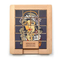 Wooden sliding puzzle titled 'Naughty & Nice' by Trove, featuring colorful tiles that create an image of a woman resembling a classic art style. The puzzle has a mechanism for sliding tiles to rearrange the image, with instructions saying 'REMOVE ME' on a central block. The design showcases intricate details, invoking a playful and nostalgic atmosphere.