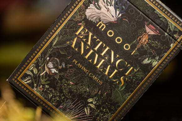 The Extinct Animals by Moooi playing cards packaging features a detailed design with various plants and flowers surrounding the title in gold lettering. The artwork conveys a deep appreciation for nature and the beauty of extinct species, making it a unique addition to any card game collection.