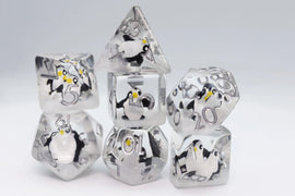 A set of six intricately designed Baby Penguin dice featuring cute penguin illustrations encased in a transparent resin material. The dice include various shapes, such as a tetrahedron and cube, with clear numerical engravings, making them perfect for tabletop games. The playful penguin designs add a fun and whimsical touch to gaming sessions.
