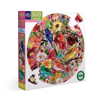 Eeboo Birds & Blossoms 500-piece round jigsaw puzzle featuring a vibrant illustration of colorful birds and assorted flowers, displayed in a colorful box. The puzzle promotes creativity and relaxation.