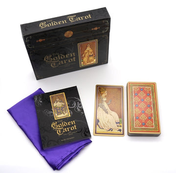 The Golden Tarot set includes a beautifully designed box, a vibrant purple cloth, a guidebook, and two tarot cards showcasing intricate artwork. The deck features rich colors and ornate details, perfect for tarot readings.