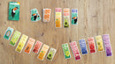 The Tucano game by Helvetiq displayed on a wooden table. Colorful game cards featuring various animals and numbers are laid out in an organized pattern, with a vibrant box artwork featuring a toucan in a tropical setting.