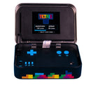 Tetris Arcade In A Tin by Fizz Creations Inc. opens to reveal a compact gaming device with a small screen displaying the Tetris logo and game mode options. The device features blue buttons for gameplay and a colorful Tetris block design on the bottom. Perfect for nostalgic gaming on the go.