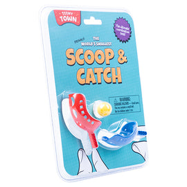 Teeny Town Scoop and Catch game by Fizz Creations Inc. featuring two colorful tiny scoops, one red and one blue, along with a small yellow ball. The packaging is bright and playful, showcasing the game's fun and engaging nature, ideal for kids. Instructions and safety warnings are visible on the back.